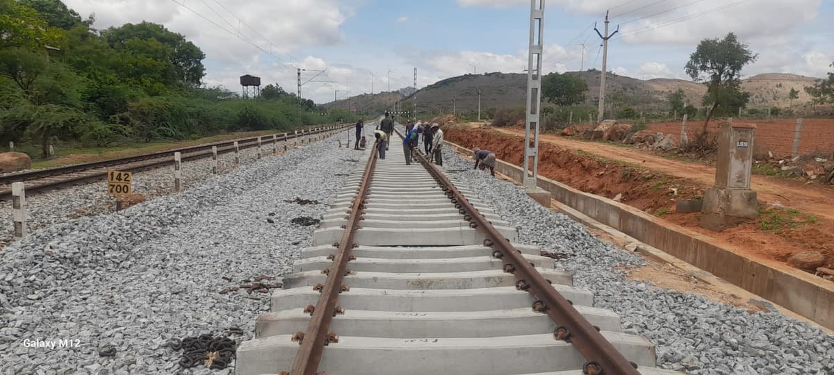Workers on newly laid railway track with concrete sleepers and ballast